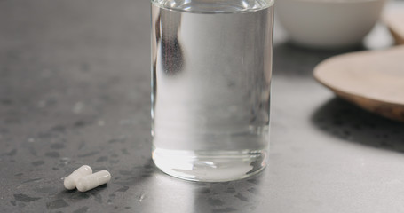 white pills and glass of water on terrazzo countertop