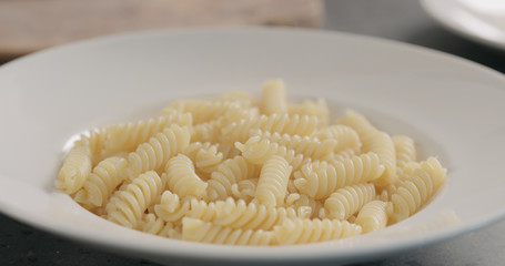 steam rising from boiled hot fusilli in white plate closeup