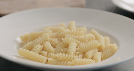 steam rising from boiled hot fusilli in white plate closeup