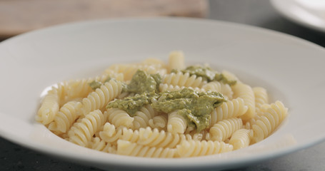 pesto sauce over fusilli in white plate closeup