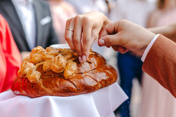 The loaf is sprinkled with salt. The bride and groom pour salt on the loaf. Fingers of the bride and groom sprinkle salt on the bread loaf. Meeting with a loaf. | YEKATERINBURG, RUSSIA - 05 JULY 2019.