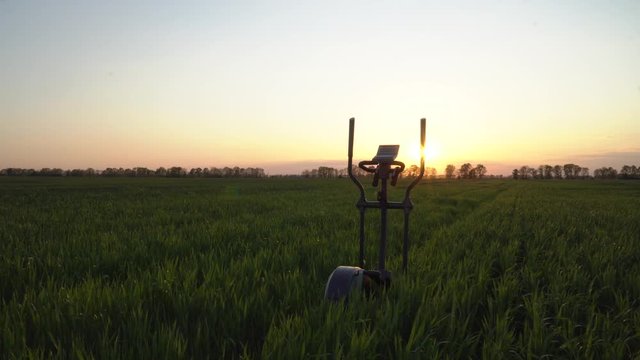 Fitness stopper orbitrek on a green field. Sunset. Dolly shot.