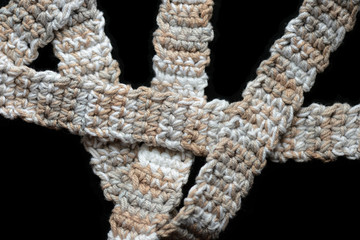 Melange yarn crocheted tape on a black background close up. Handmade concept. Top view