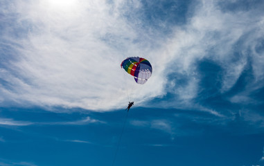 Parasailing, or parascending or para kiting, a recreational kiting activity, flying in the clear blue sky. In Patong beach, Phuket, Thailand. 