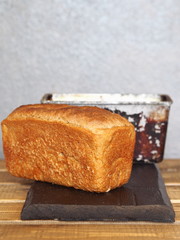 Freshly baked diet rye bread with a baking dish on a wooden table with a gray background.