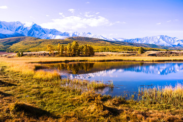 lake and mountains, Altai, autumn day. Reflections in the lake, yellow withered grass.