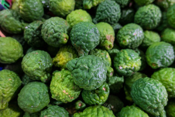 Kaffir lime, makrut lime, bergamot or Mauritius papeda, citrus fruit native to tropical Southeast Asia and southern China, full frame in a bucket, in farmer's market.