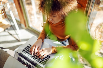 Top view of woman surfing on internet while sitting in cafe. Hands are on keyboard.