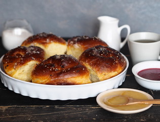 Homemade cake.Buns sprinkled with sesame and sugar syrup with ingredients on a dark wooden table with a gray background.