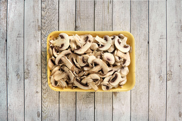Pack with mushrooms on a kitchen table on wooden culinary background. Top view.
