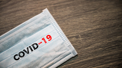 Obraz premium Inscription Covid-19 on Surgical mask with rubber ear straps. antivirus medical mask for protection covid-19. Protection corona virus concept.