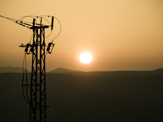 High voltage towers on coast at sunset