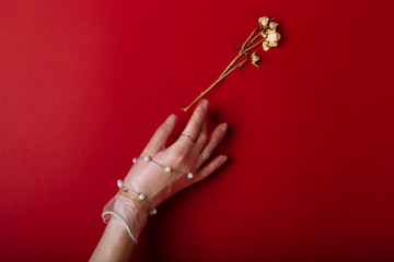 Fashion art hand woman in the glove with Jewelry in summer time and flowers behind her hand with bright contrasting makeup. Creative beauty photo hand skincare