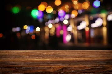 background Image of wooden table in front of abstract blurred restaurant lights