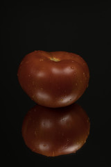 Tomato on black reflective studio background. Isolated black shiny mirror background for every concept.
