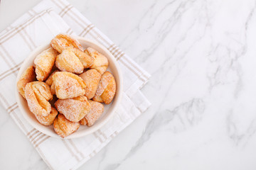 Freshly baked cottage cheese and sugar cookies (triangles, angles) in a marble background. Crow's feet.