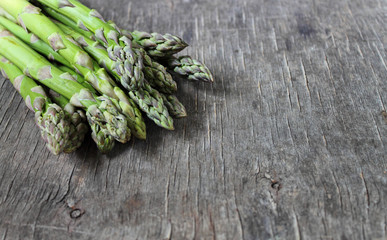 Banches of fresh green asparagus on a wooden background, top view