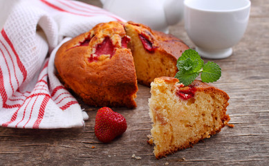 Fresh, homemade cake with strawberris, decorated with mint wooden background
