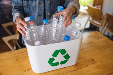 A woman collecting and separating recyclable garbage plastic bottles into a trash bin at home