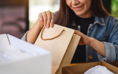 Closeup image of a woman opening and looking inside shopping bag at home for delivery and online...