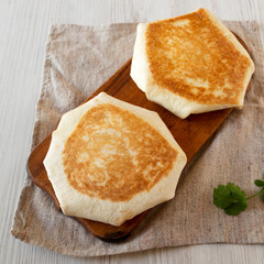 Crispy Homemade Beef Crunchwrap Quesadilla on a rustic wooden board on a white wooden background, high angle view. Copy space.