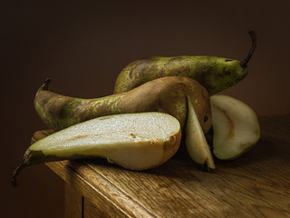 Juicy green pear, on a wooden table, with a dark background, soft light. Imitation of a Dutch kitchen still life. Mono food. - 351824876