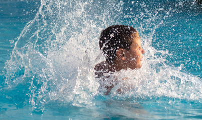 A boy swims in the pool with spray