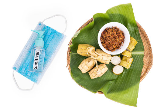 Ketupat, rice dumpling, lemang, serunding with sanitizer and face mask. Restricted celebration during covid-19 pandemic