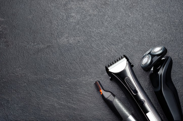 Electric shaver, trimmer, top view of arrangement of various barber tools on grey background.