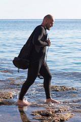 underwater photographer with a scuba cam wearing a neopren swimming suit and fins getting ready for...