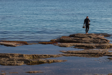 underwater photographer with a scuba cam wearing a neopren swimming suit and fins getting ready for diving. Diver cleaning his Scuba gear in Majorca.  Water sports photos. Scuba diving resources. 