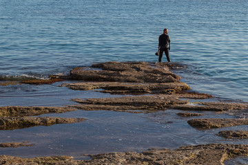 underwater photographer with a scuba cam wearing a neopren swimming suit and fins getting ready for diving. Diver cleaning his Scuba gear in Majorca.  Water sports photos. Scuba diving resources. 