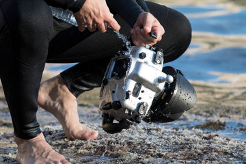 underwater photographer washing his scuba cam and scuba diving gear with water after an underwater...