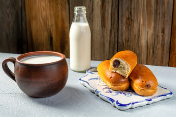 Breakfast rolls with chocolate filling and milk on a wooden rustic background