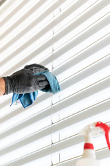 caucasian man cleaning professionally cleaning window blinds with a micro fiber cloth and cleaning detergent