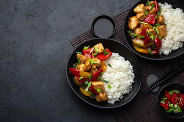 Sweet ad sour chicken served with steamed rice in black bowl