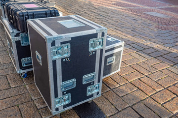 Boxes with reinforced corners, handles and wheels on the city sidewalk. Containers for concert...