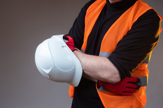 A Man In An Orange Vest Is Holding A Construction Helmet. Builde