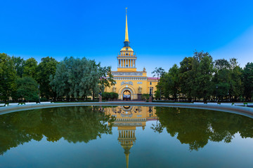 Fototapeta premium Saint Petersburg. Russia. The Admiralty building is reflected in the water. Admiralty on the background of water in the fountain. A Golden spire with a ship against the blue sky. Summer in Petersburg.