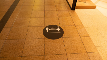 A social distance warning sign on the ground in a shopping mall.The mark was placed because of the coronavirus.