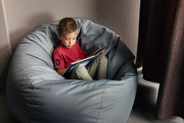 Fototapeta premium Caucasian boy learns to read a book. My first book