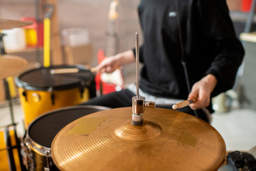 Obraz premium Hand of young musician in black hoodie holding drumstick over cymbals
