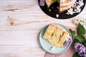 Biscuit cake with cream, impregnated with coconut and pineapple, decorated with lilac flowers.