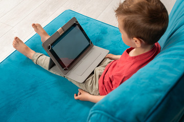 Fototapeta premium Preschooler watches tablet at home. Leisure at home