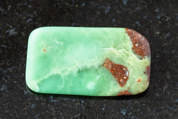 closeup of sample of natural mineral from geological collection - tumbled Chrysoprase rock on black...