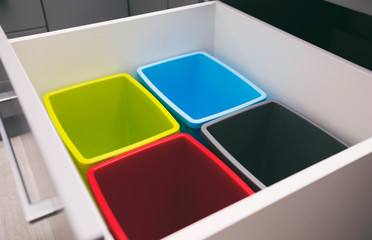 Four empty plastic trash bins in the shelf in the kitchen for sorting garbage