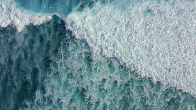 Slow motion top down aerial view of the ocean giant waves, foaming and splashing