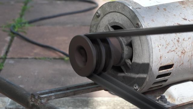 Rusty and old water pump motor working, Rotating pulley and belt on air pump machine