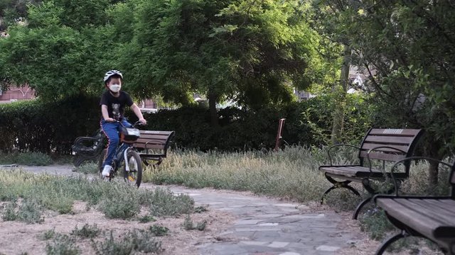 Chinese child with mask cycling outdoor for exercise in coronavirus period