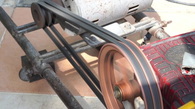 Rusty and old water pump motor working, Rotating pulley and belt on air pump machine